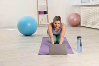 Photo of Online fitness trainer. Woman watching tutorial on laptop at home