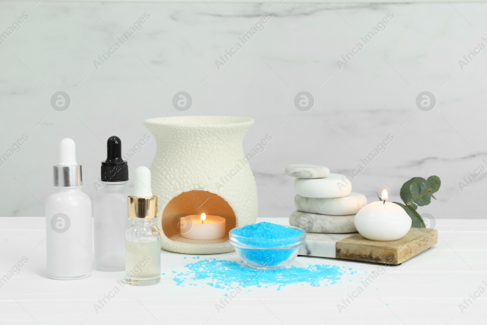 Photo of Different aromatherapy products and burning candles on white wooden table