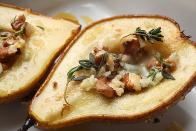 Tasty baked pears with nuts, blue cheese, thyme and honey on plate, closeup