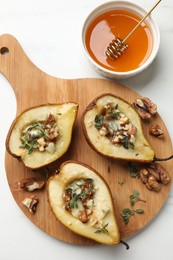 Tasty baked pears with nuts, blue cheese, thyme and honey on white table, flat lay