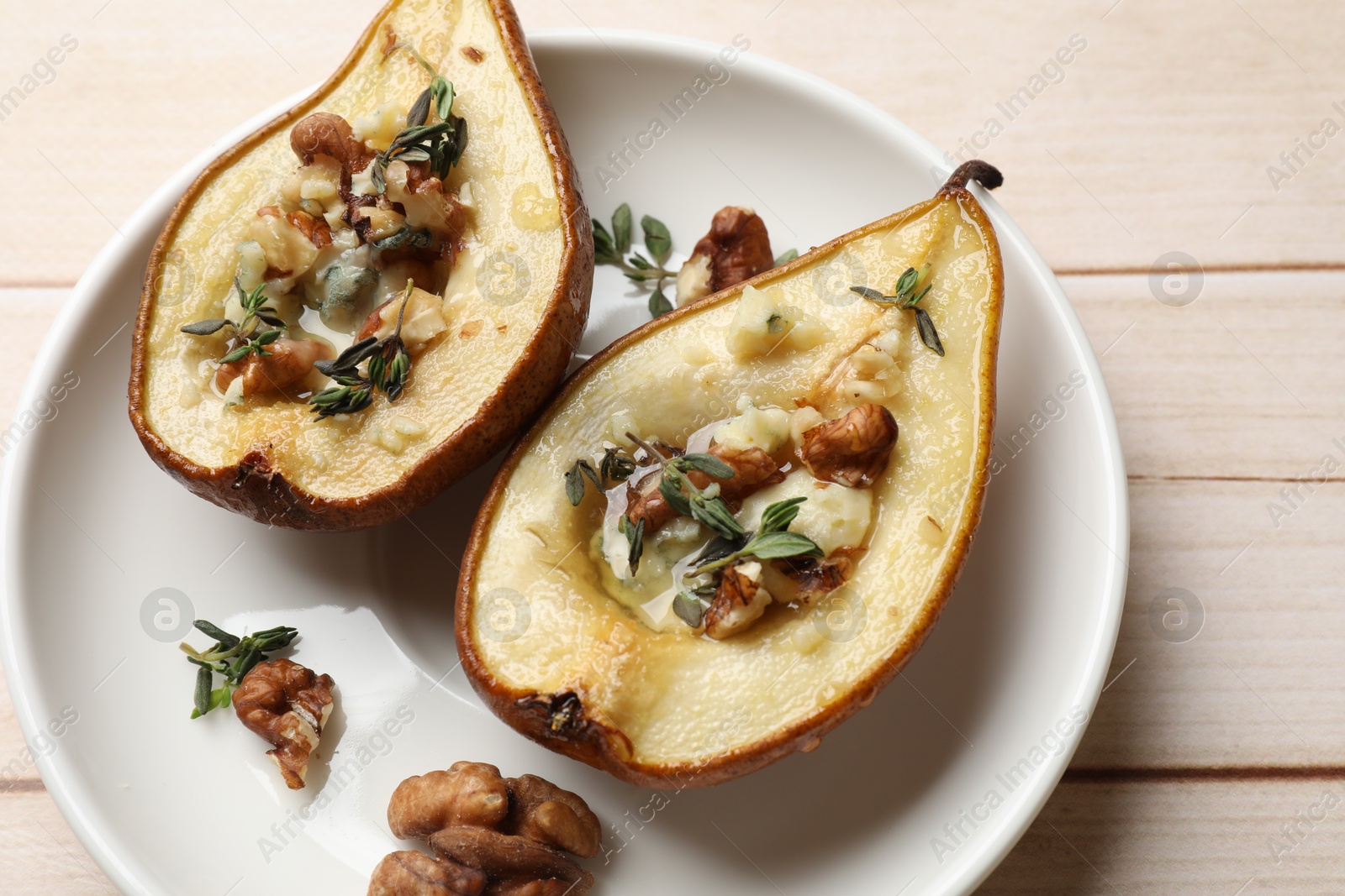 Photo of Tasty baked pears with nuts, blue cheese, thyme and honey on wooden table, top view