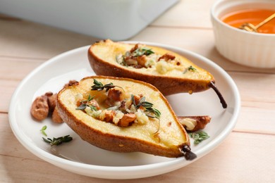 Photo of Tasty baked pears with nuts, blue cheese, thyme and honey on wooden table, closeup