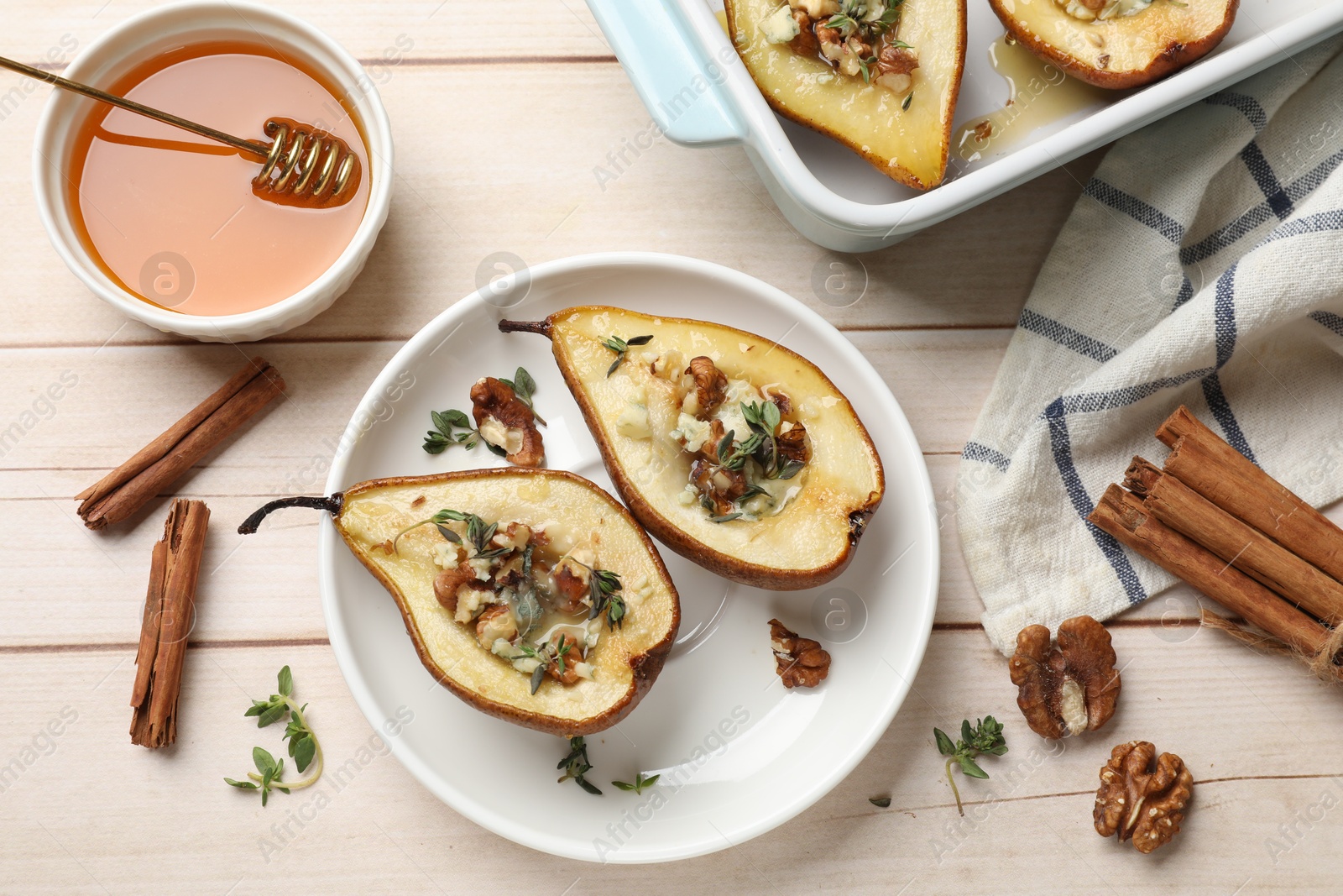 Photo of Tasty baked pears with nuts, blue cheese, thyme and honey in baking dish on wooden table, flat lay