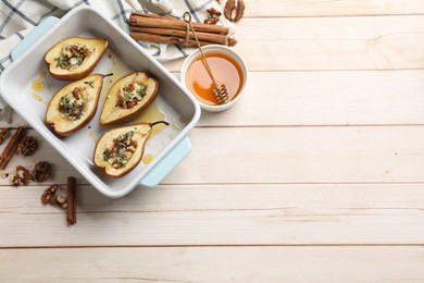 Tasty baked pears with nuts, blue cheese, thyme and honey in baking dish on wooden table, flat lay. Space for text