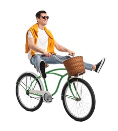 Smiling man in sunglasses having fun while riding bicycle with basket on white background