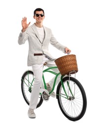 Smiling man in sunglasses riding bicycle with basket on white background