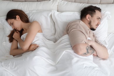 Photo of Offended couple after quarrel ignoring each other in bed. Relationship problem