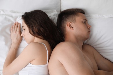 Photo of Offended couple after quarrel ignoring each other on bed, top view. Relationship problem