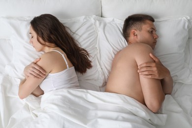 Photo of Offended couple after quarrel ignoring each other in bed, top view. Relationship problem