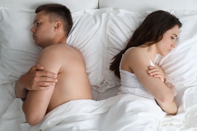 Photo of Offended couple after quarrel ignoring each other in bed, top view. Relationship problem