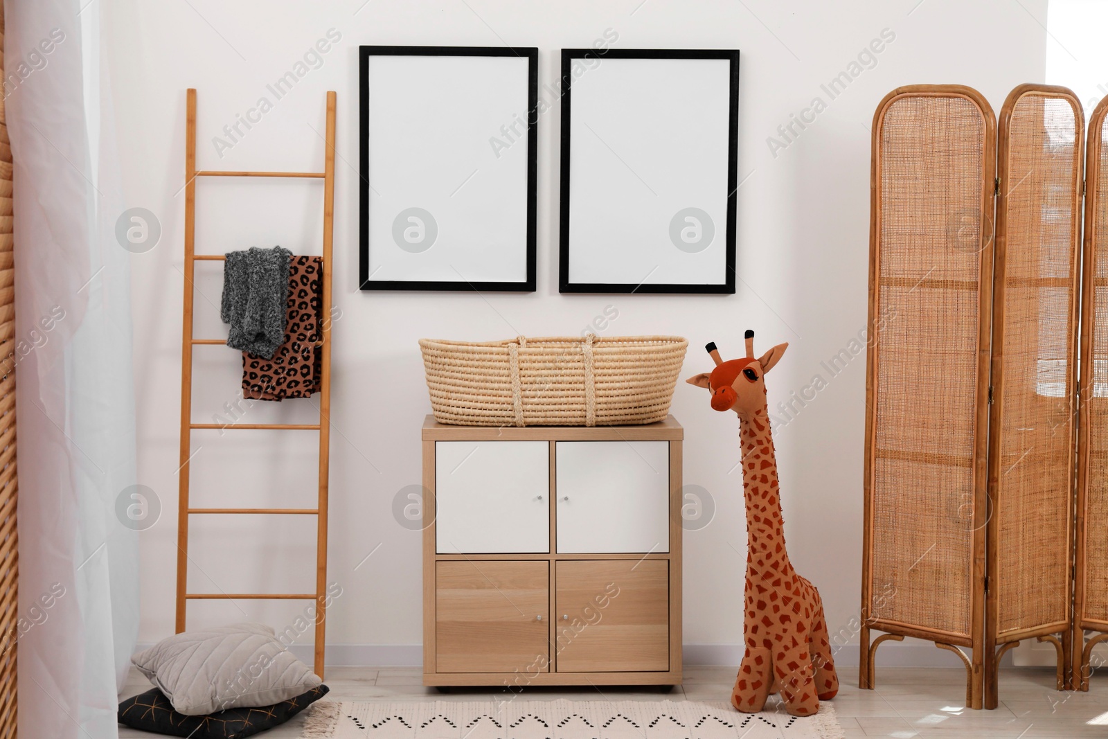 Photo of Child's room interior with modern furniture, toy giraffe and empty frames on wall
