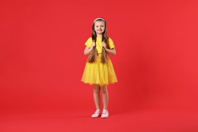 Cute little dancer with long hair on red background
