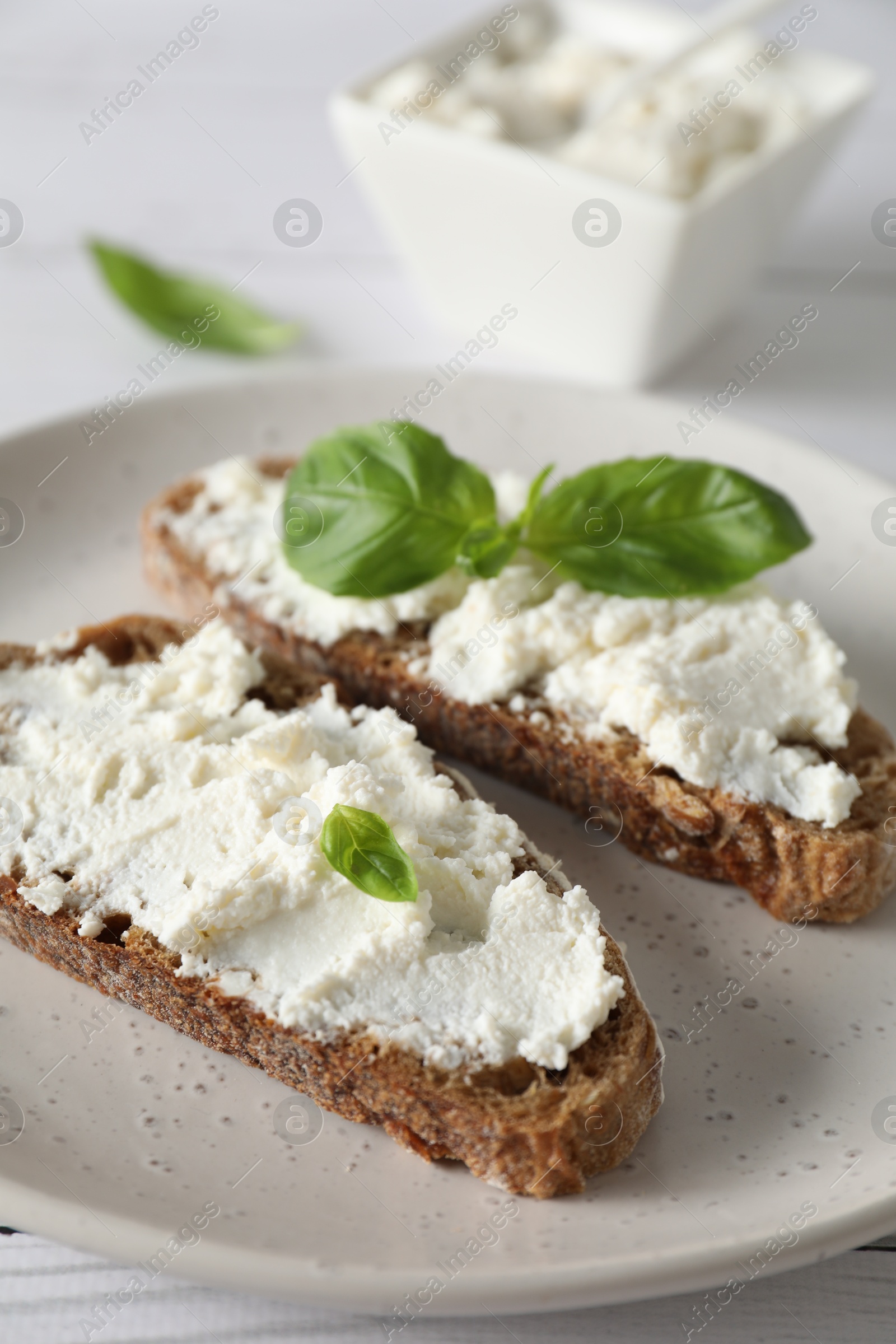 Photo of Bruschettas with ricotta cheese and basil on white wooden table, closeup