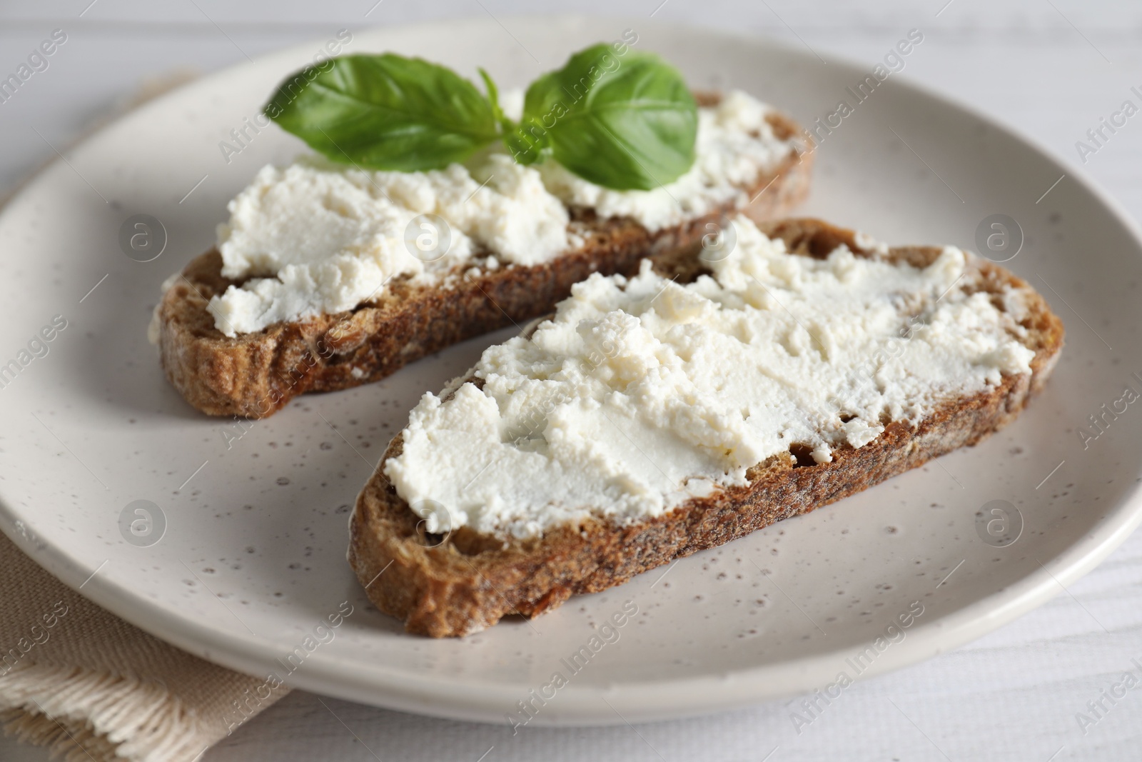 Photo of Bruschettas with ricotta cheese and basil on white wooden table, closeup