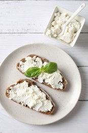 Photo of Bruschettas with ricotta cheese and basil on white wooden table, top view