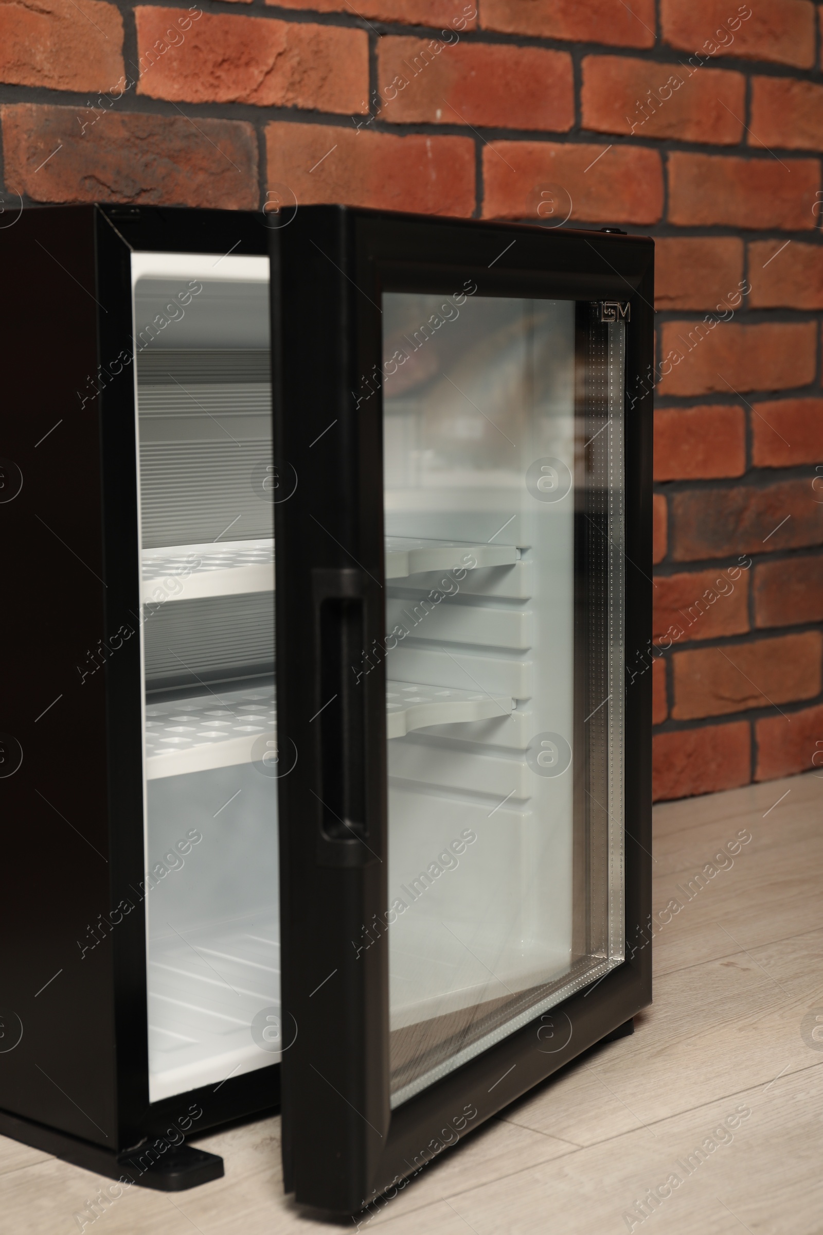 Photo of Empty mini refrigerator near brick wall, closeup