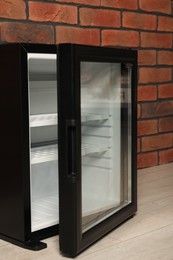 Photo of Empty mini refrigerator near brick wall, closeup