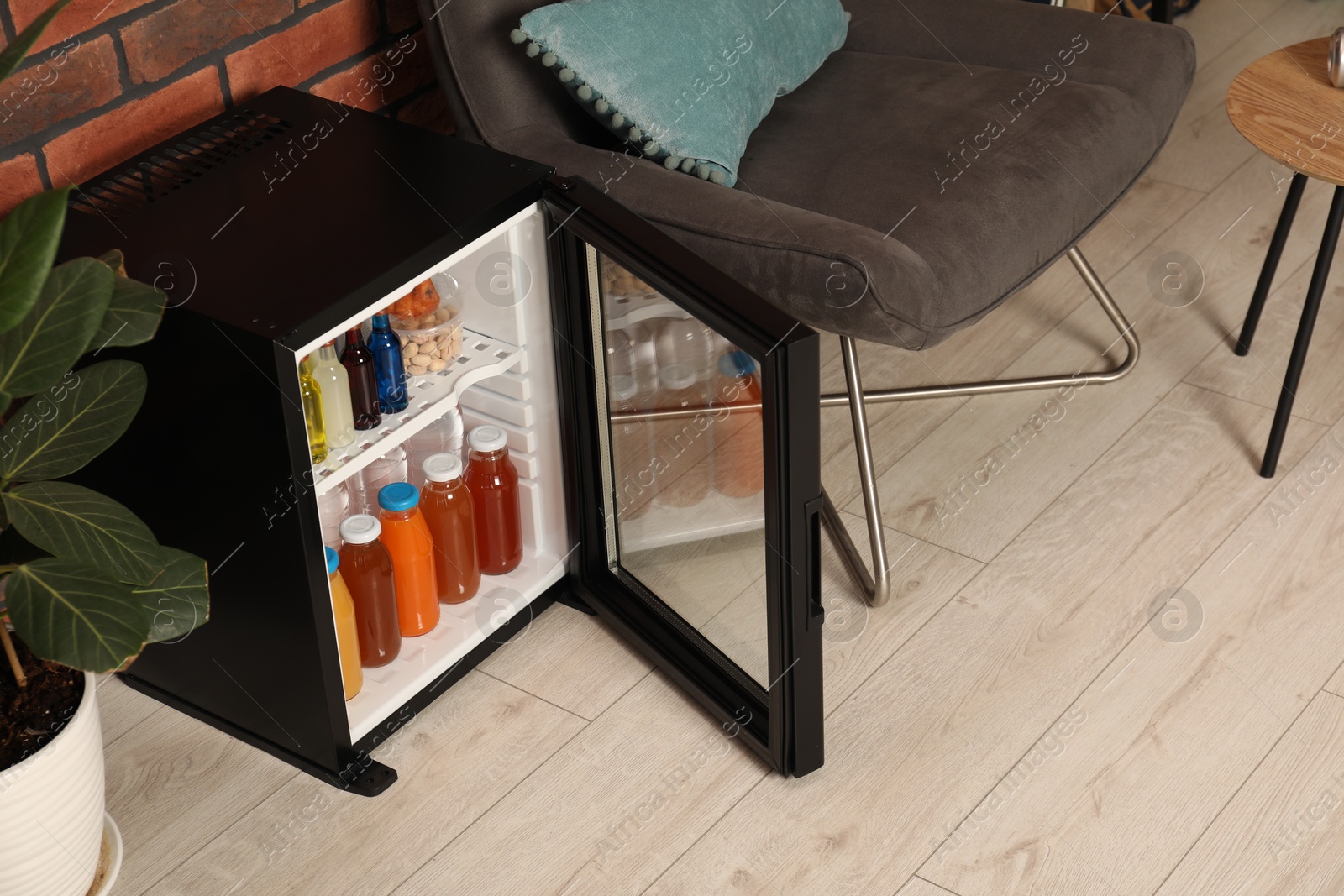 Photo of Mini refrigerator with drinks and snacks indoors