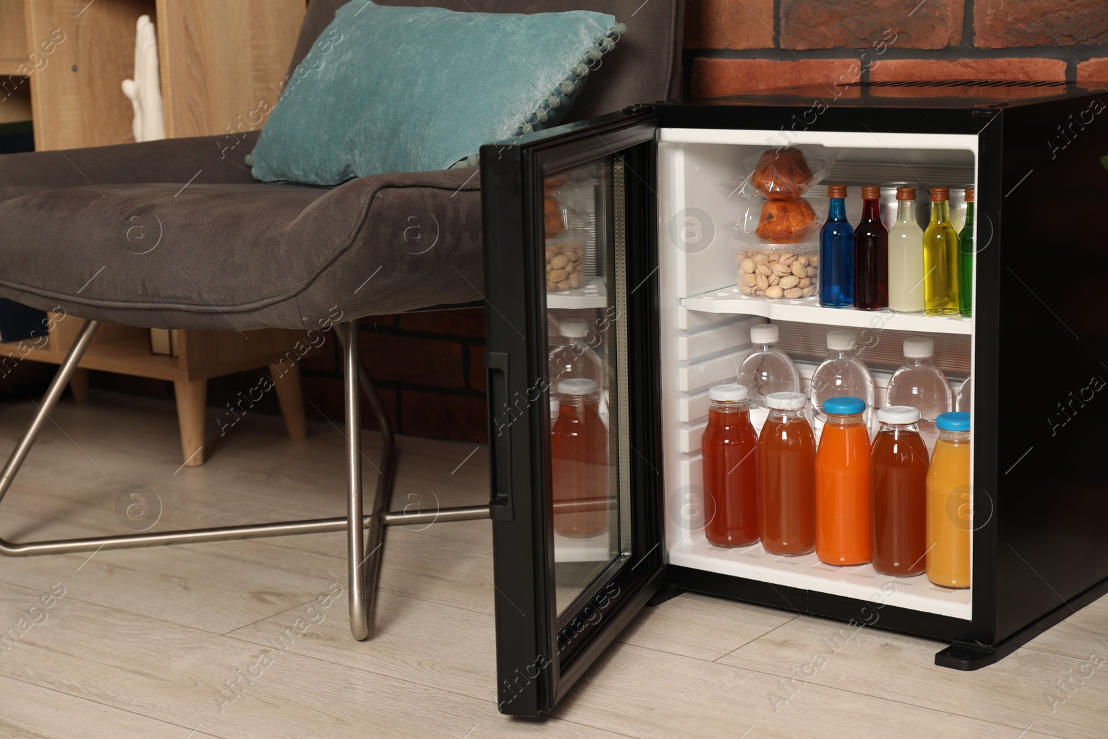 Photo of Mini refrigerator with drinks and snacks indoors