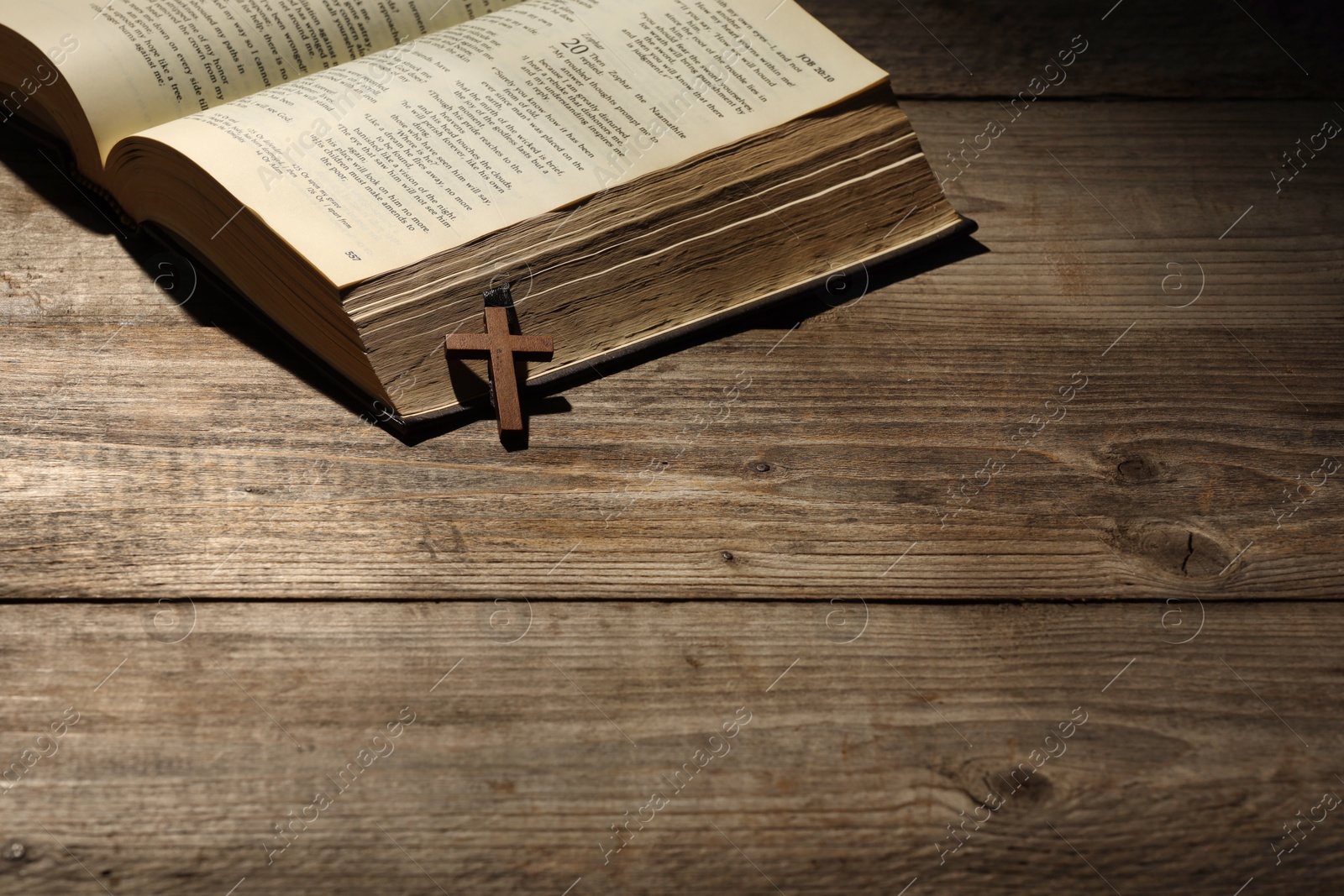 Photo of Bible and cross on wooden table, space for text. Religion of Christianity