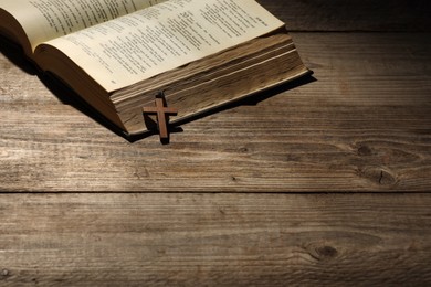 Bible and cross on wooden table, space for text. Religion of Christianity