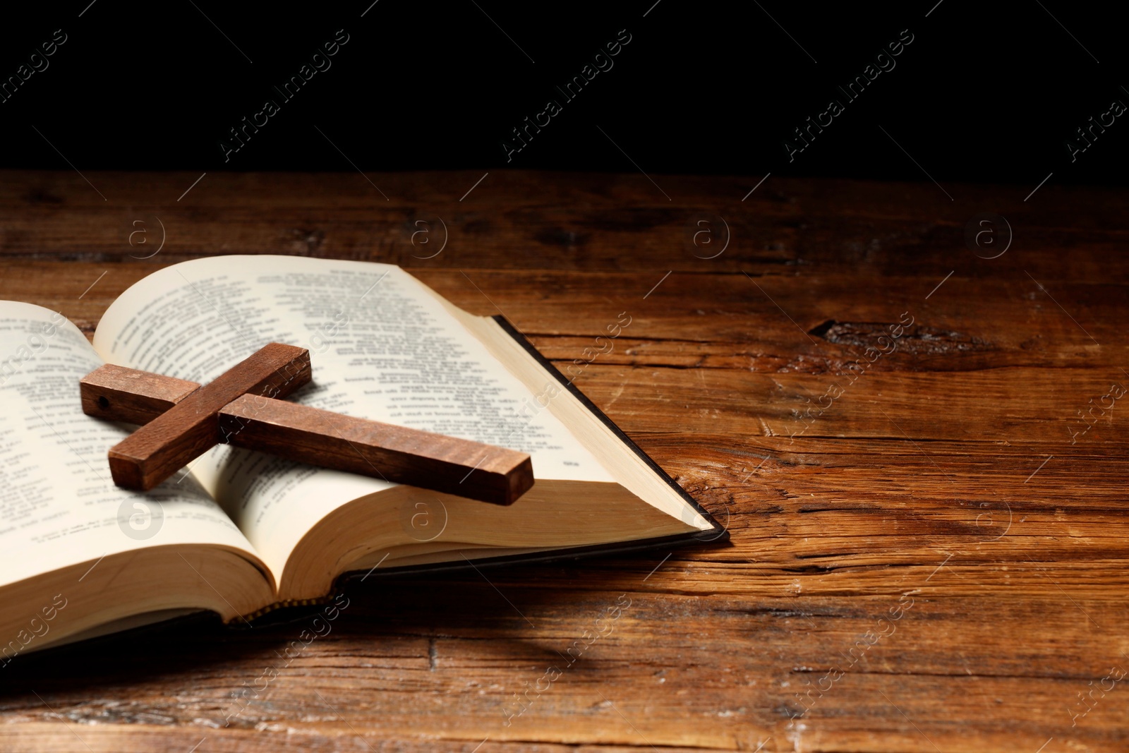 Photo of Bible and cross on wooden table, space for text. Religion of Christianity
