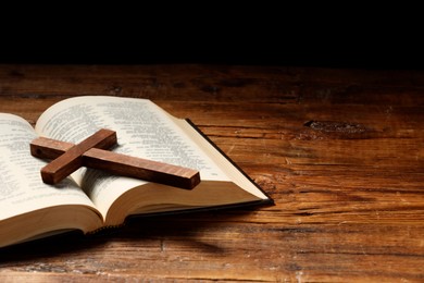 Photo of Bible and cross on wooden table, space for text. Religion of Christianity