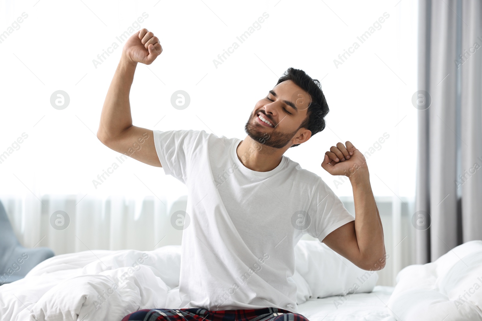 Photo of Good morning. Happy man stretching on bed at home