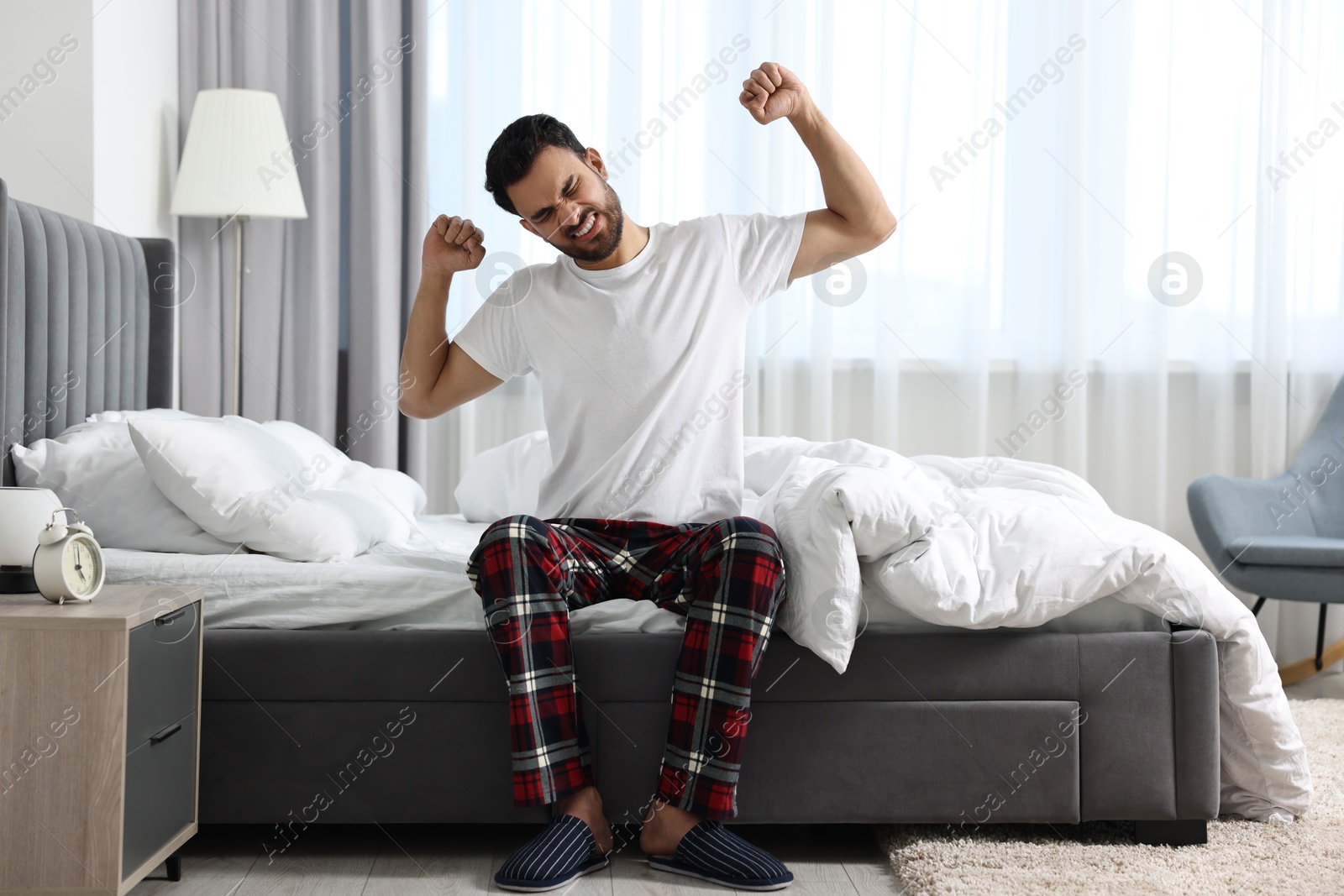 Photo of Man stretching and yawning on bed at morning