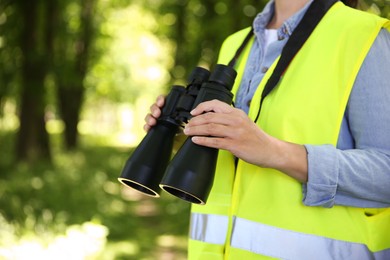 Forester with binoculars examining plants in forest, closeup. Space for text