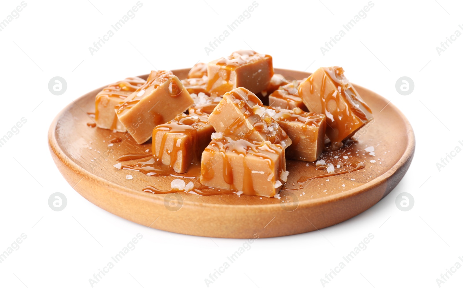 Photo of Plate with tasty candies, caramel sauce and salt isolated on white