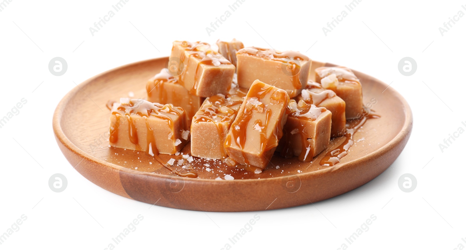 Photo of Plate with tasty candies, caramel sauce and salt isolated on white