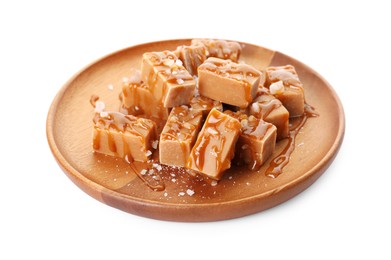 Photo of Plate with tasty candies, caramel sauce and salt isolated on white