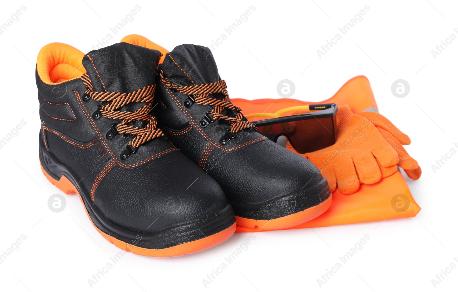 Photo of Pair of working boots, gloves, protective goggles and reflective vest isolated on white