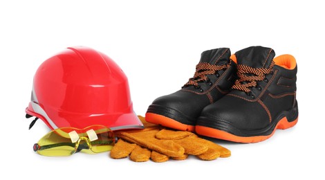 Photo of Pair of working boots, hard hat, gloves and protective goggles isolated on white