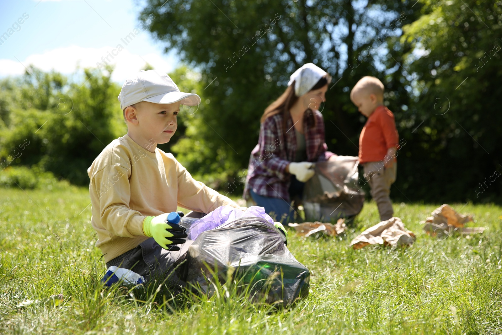 Photo of Mother and her children with plastic bags collecting garbage in park