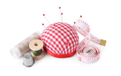 Photo of Pincushion, sewing pins, measuring tape, spools of threads and thimble isolated on white