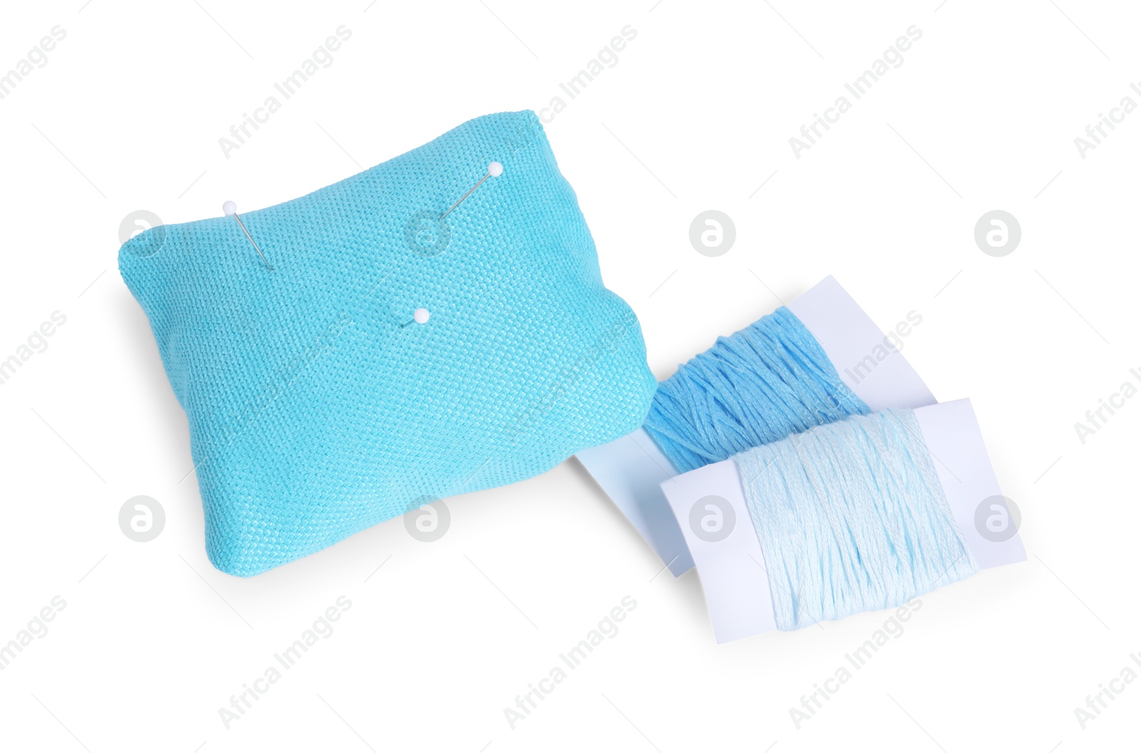 Photo of Light blue pincushion with sewing pins and threads isolated on white, above view