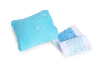 Photo of Light blue pincushion with sewing pins and threads isolated on white, above view