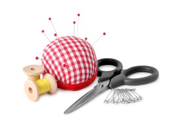 Photo of Pincushion with sewing pins, scissors, spools and thread isolated on white