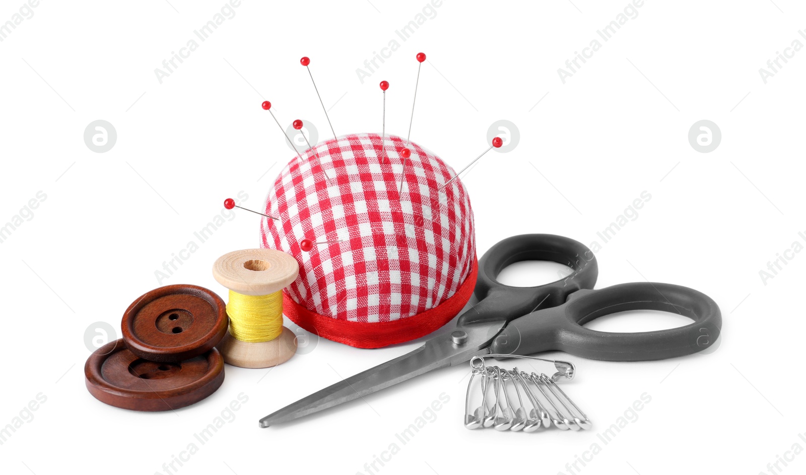 Photo of Pincushion with sewing pins, scissors, spool of thread and buttons isolated on white