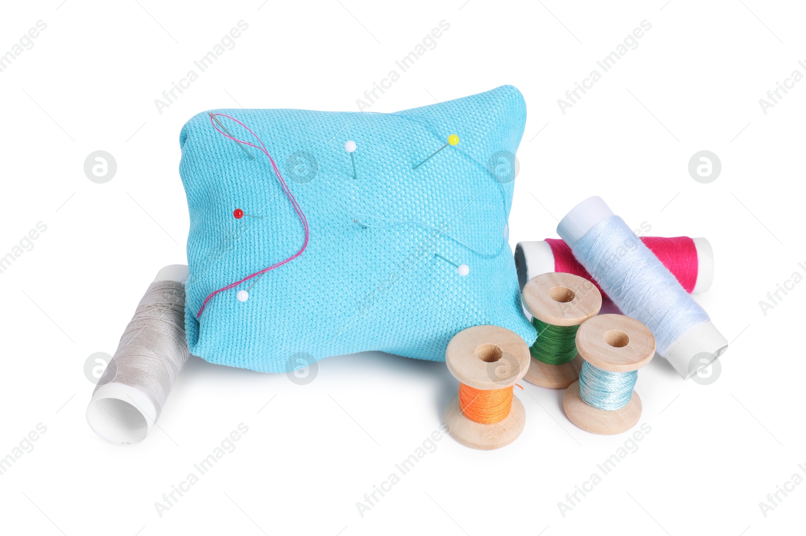 Photo of Pincushion, sewing pins, needle and spools of threads isolated on white
