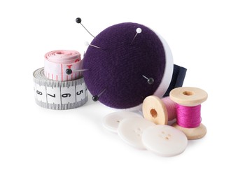 Photo of Pincushion, sewing pins, spools of threads, measuring tapes and buttons isolated on white