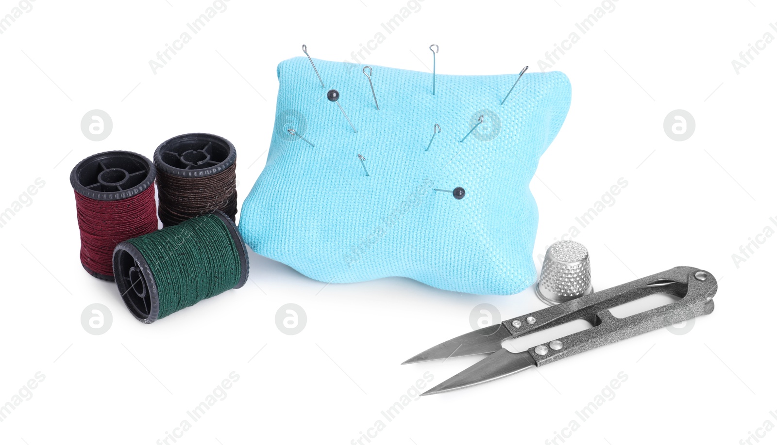 Photo of Pincushion, sewing needles, pins, cutter, thimble and spools of threads isolated on white