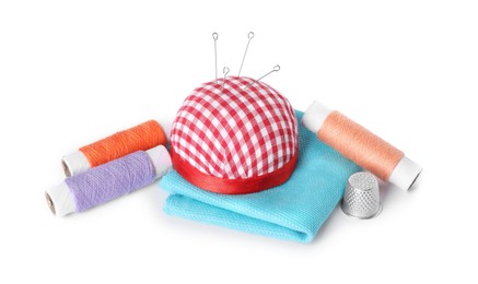 Pincushion, sewing needles, spools of threads, cloth and thimble isolated on white