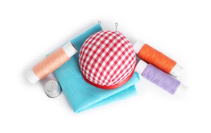 Pincushion, sewing needles, spools of threads, cloth and thimble isolated on white, top view