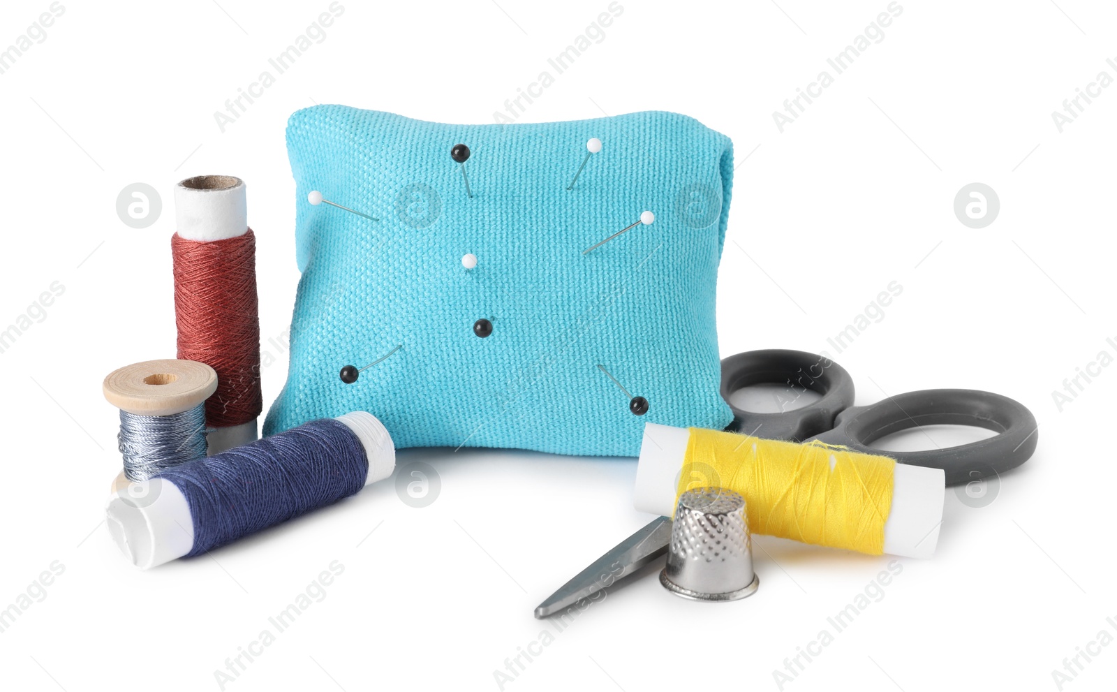 Photo of Pincushion, sewing pins, spools of threads, scissors and thimble isolated on white