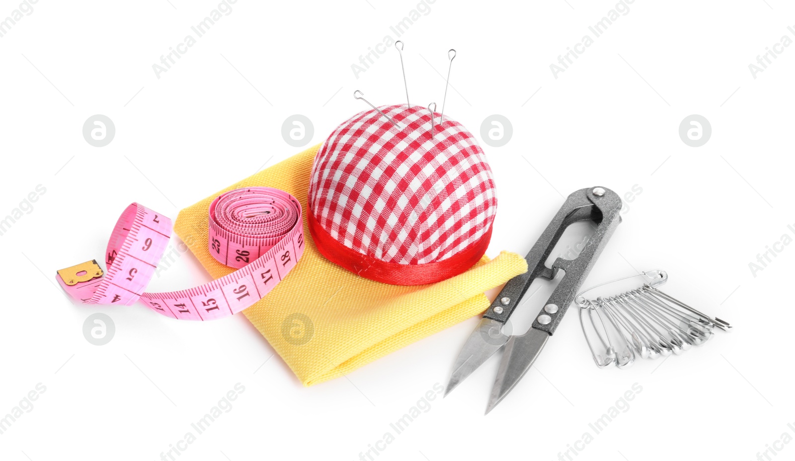 Photo of Pincushion, sewing needles, cutter, safety pins, cloth and measuring tape isolated on white