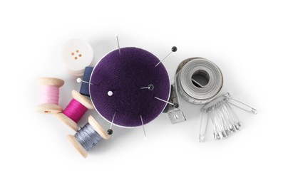 Pincushion, pins and other sewing tools isolated on white, top view