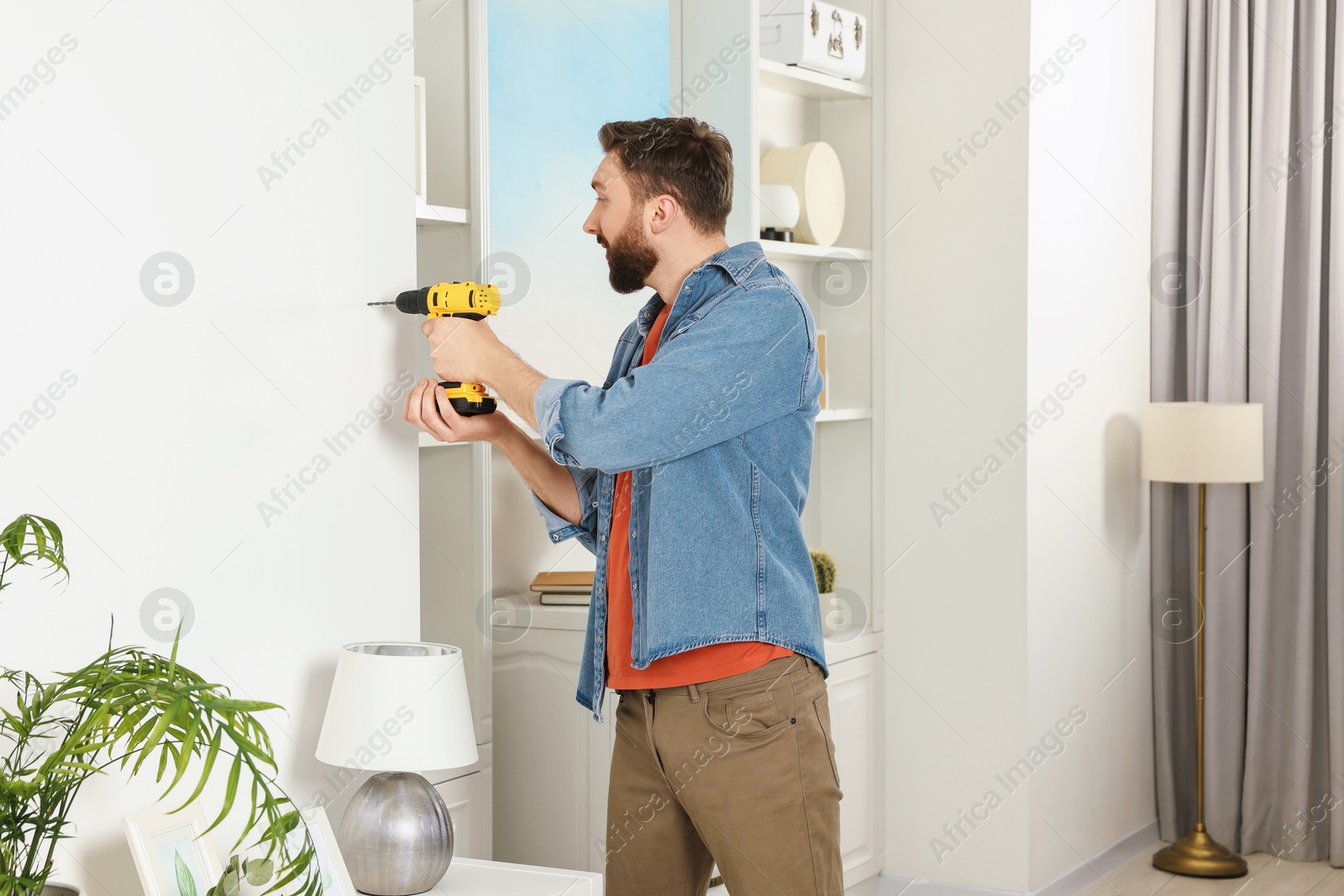 Photo of Man working with drill and wall at home